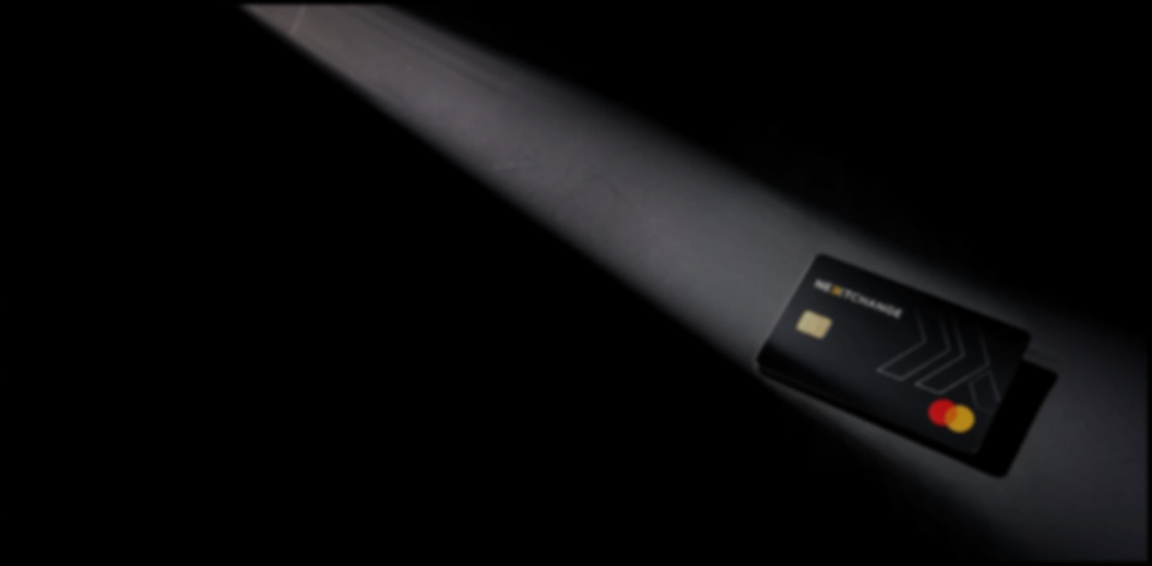 NextChange Mastercard illuminated by a spotlight on a dark surface